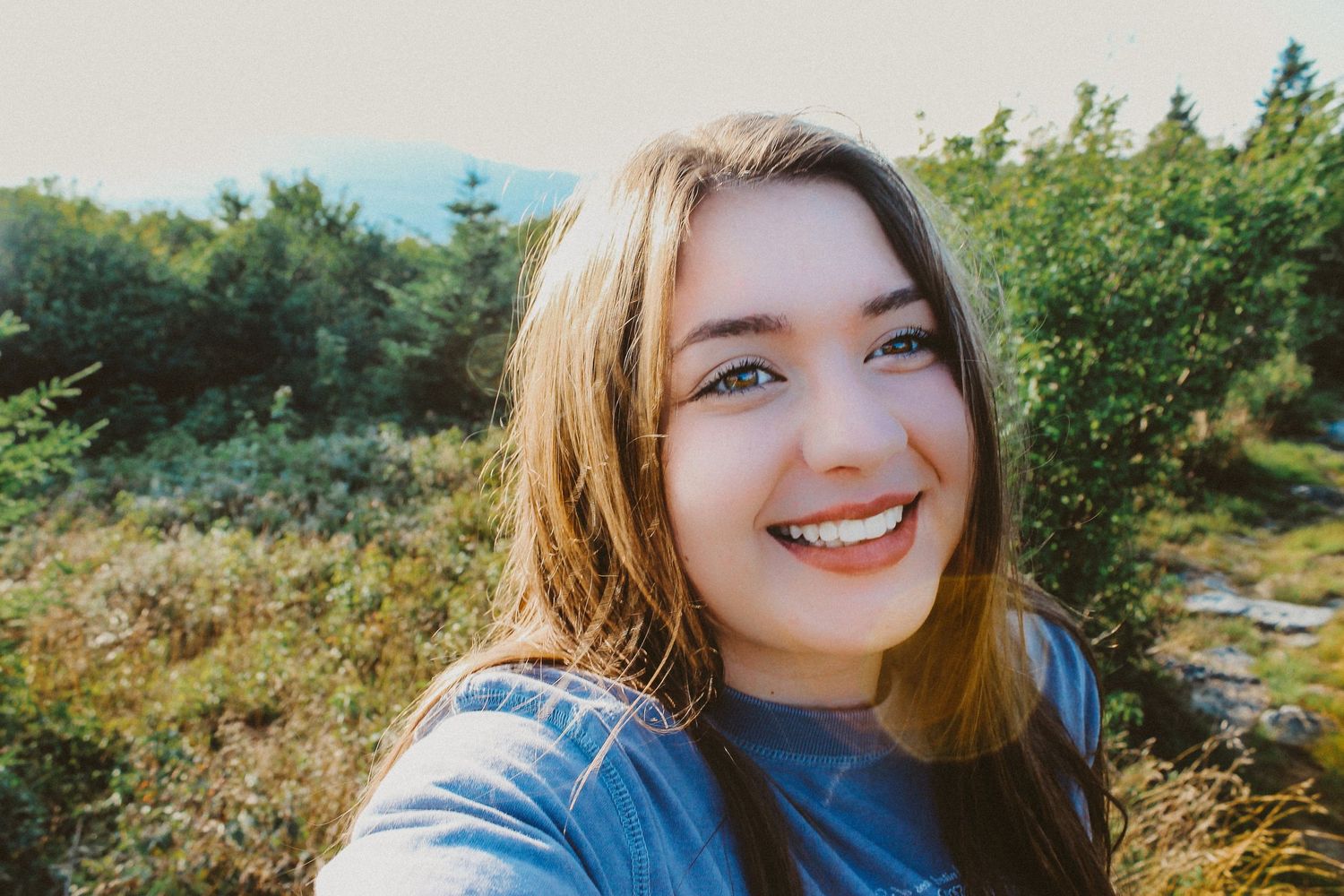Scenic outdoor portrait session in natural lighting with greenery and blue sky.