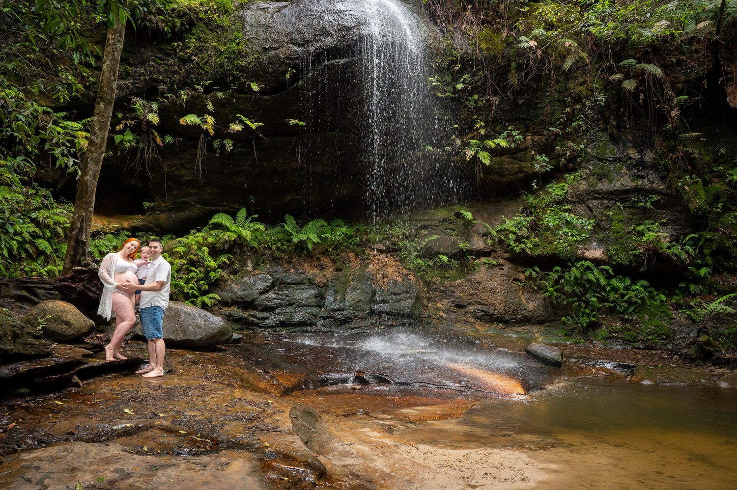 A family maternity photoshoot by the waterfall