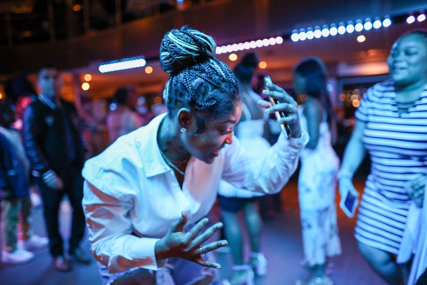 A dancer performs with passion under blue nightclub lights with a crowd in the background.