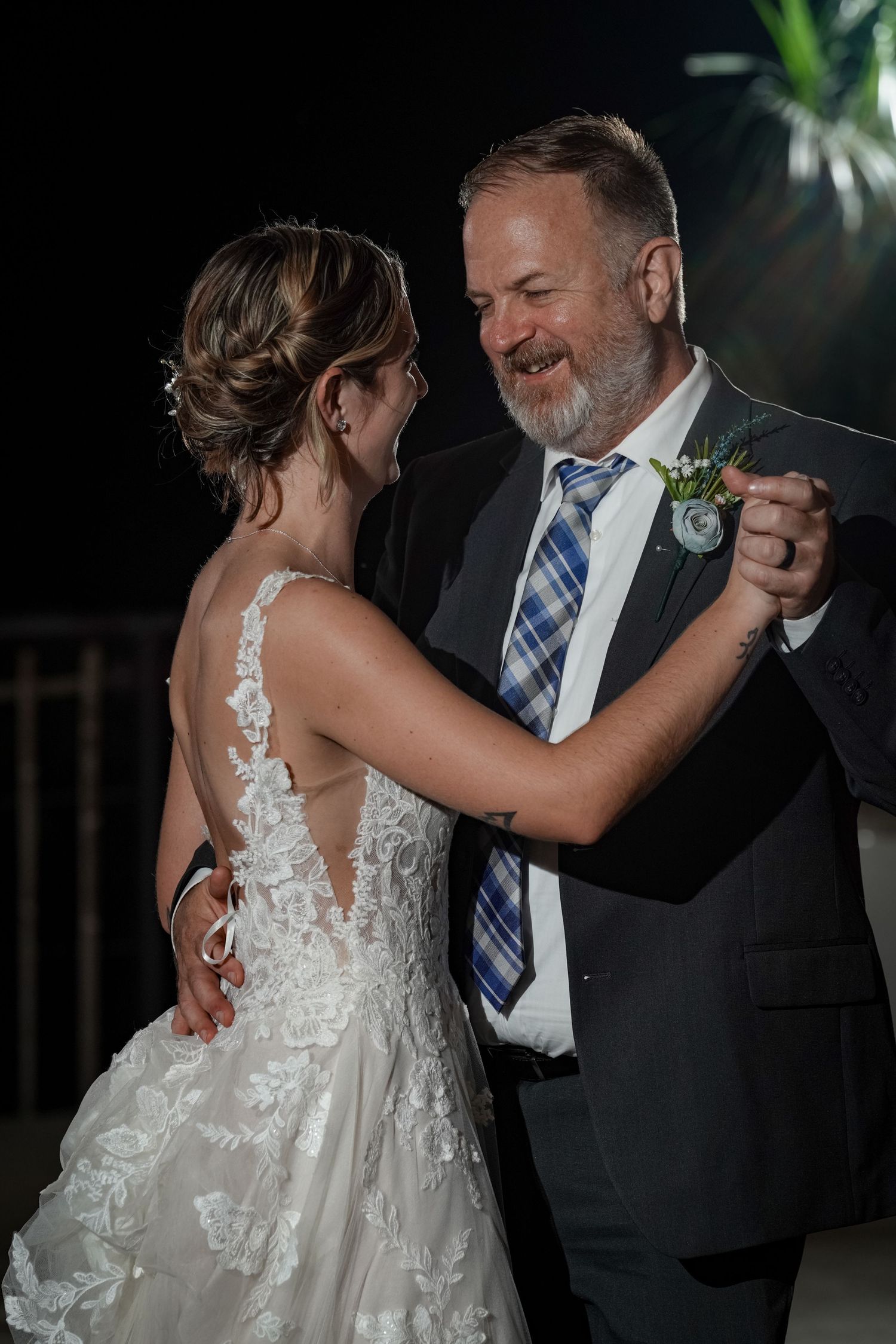 A person in a wedding dress dances with someone wearing a suit and blue tie.