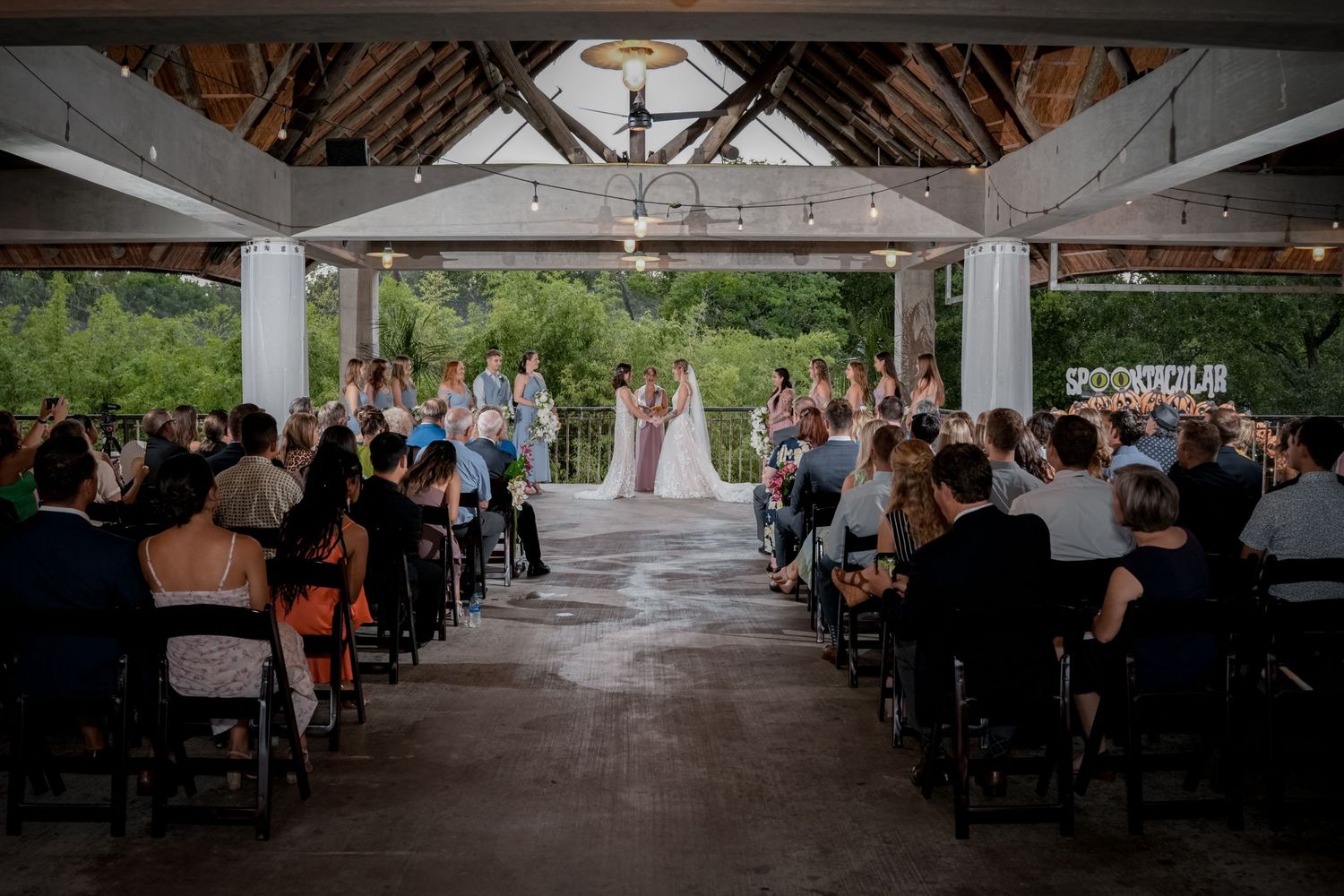 Wedding ceremony setup under a covered pavilion with guests seated in rows.