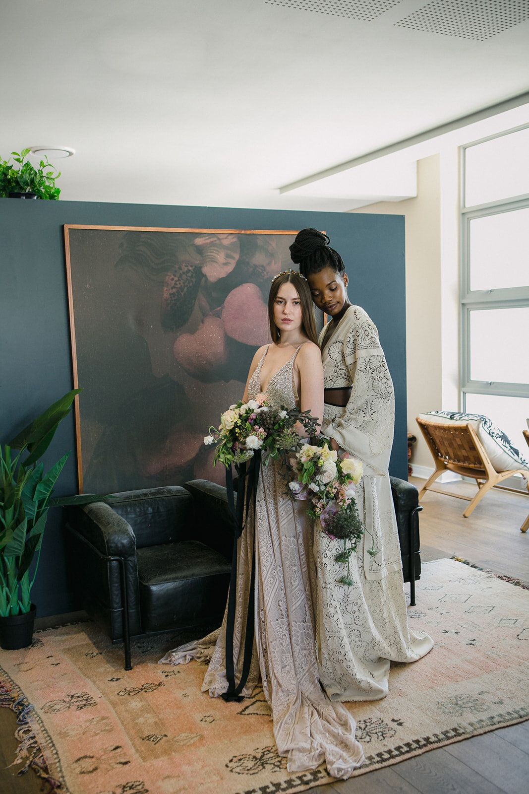 An interracial bridal couple in their wedding attire and with floral bouquets.