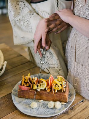 A couple cutting their orange and almond wedding cake.