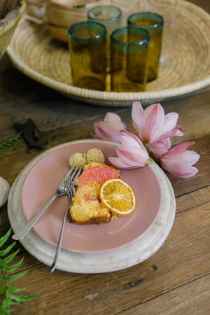 A slice of Almond and Orange Moroccan cake served on a dusty pink plate with orchids.