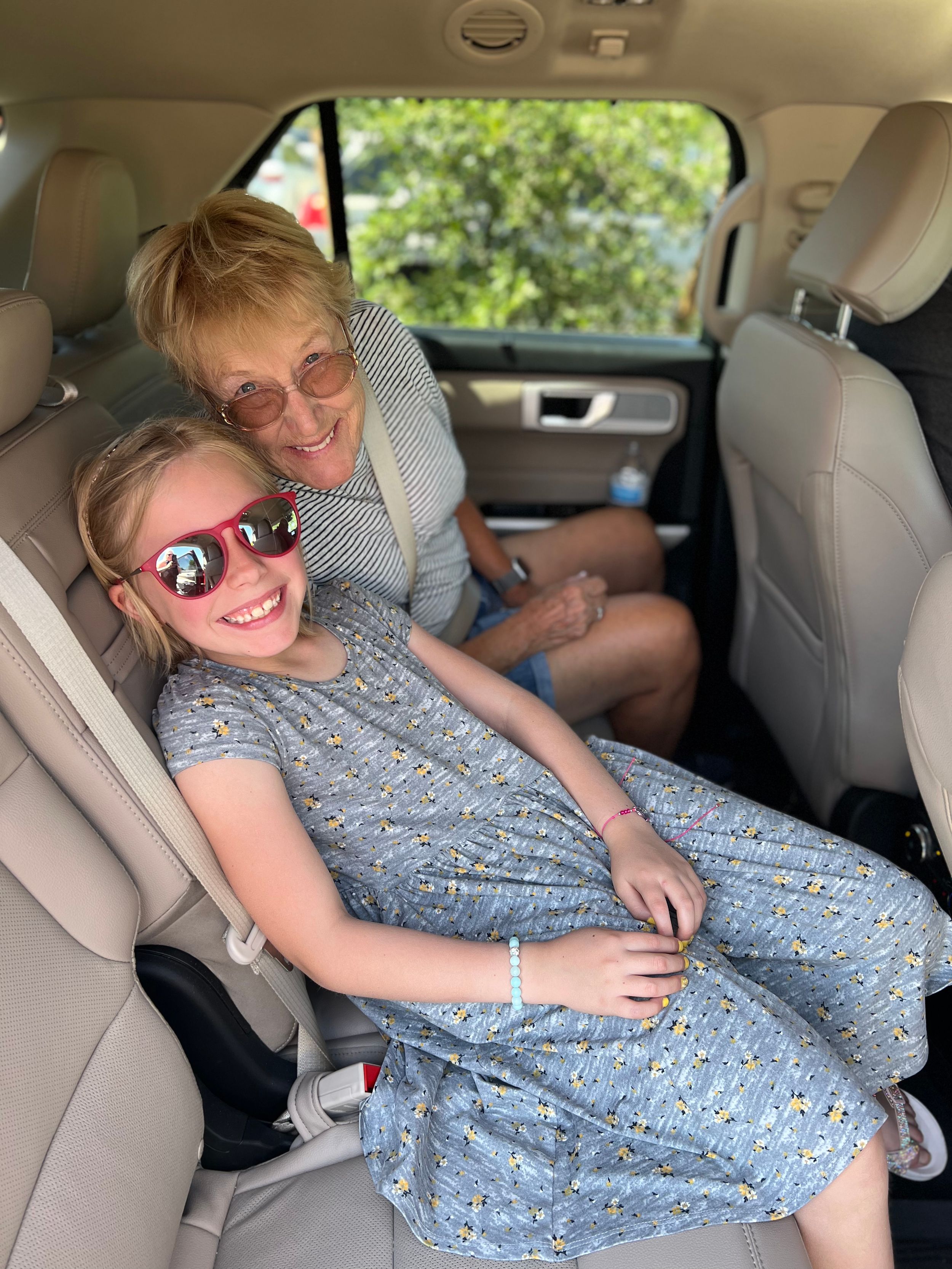 Person relaxing across car back seat wearing a blue floral dress.