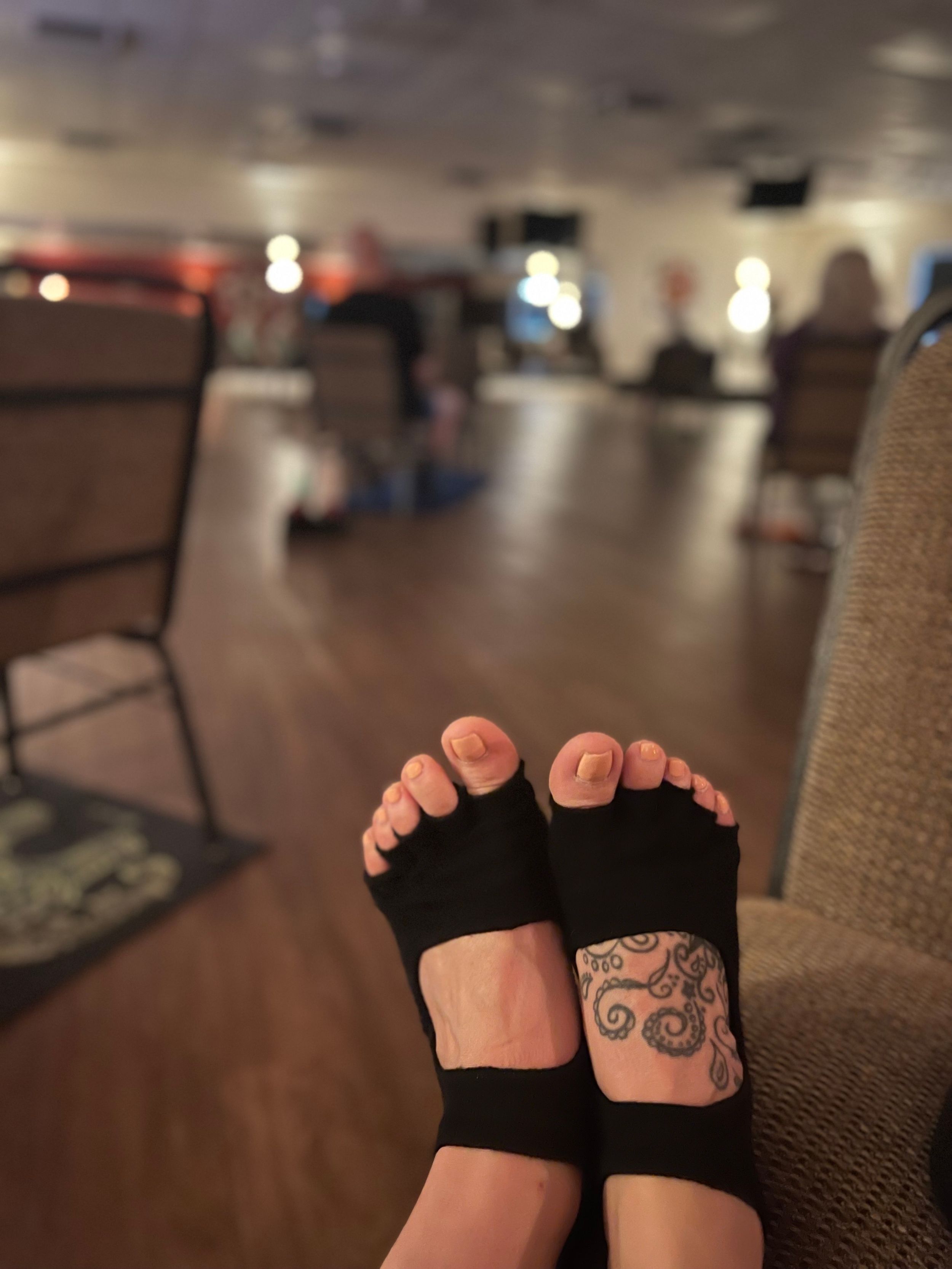 Close-up of feet with decorative tattoo in a dimly lit room.