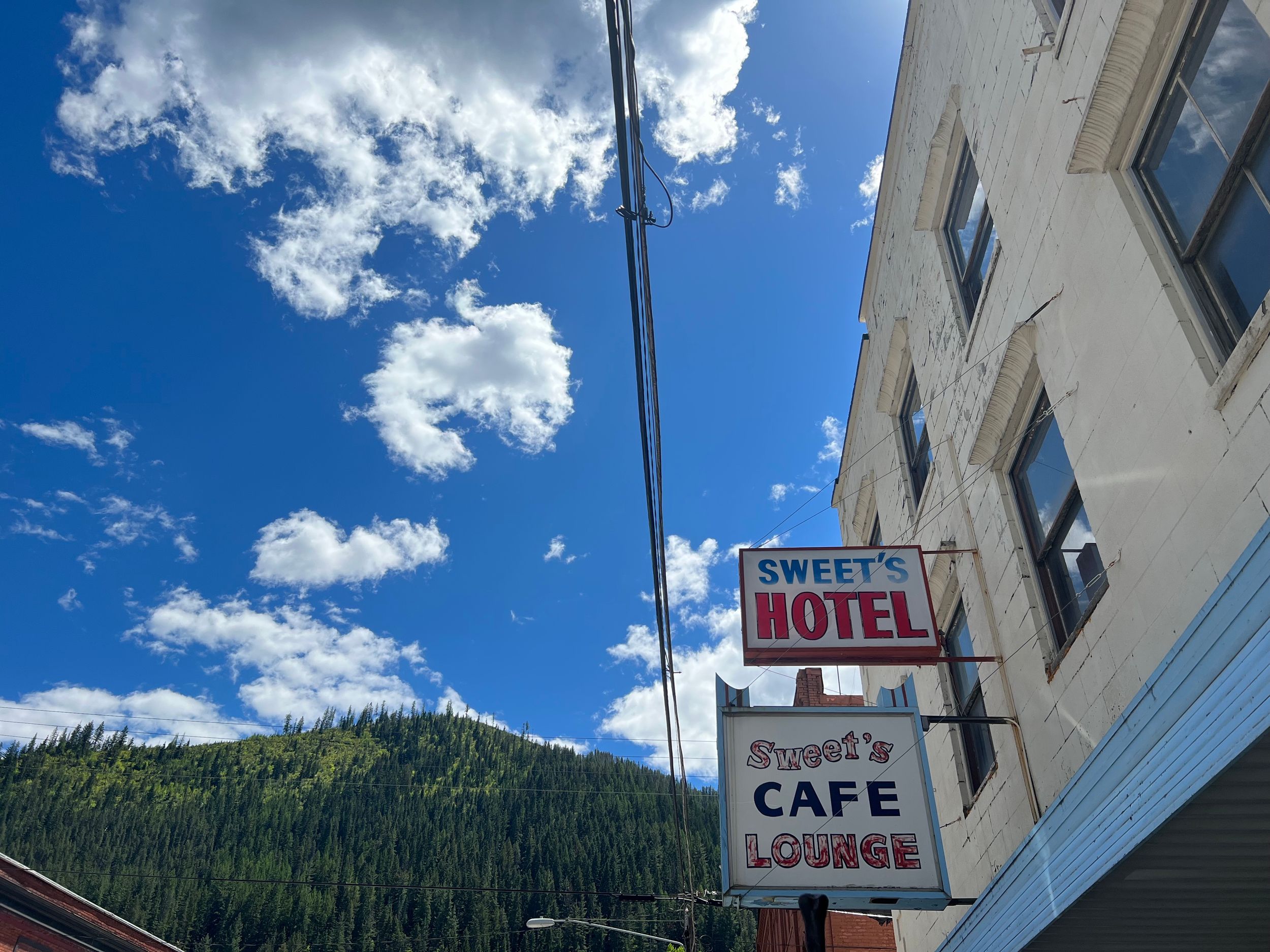 Vintage motel and cafe signs against bright blue sky with white clouds.