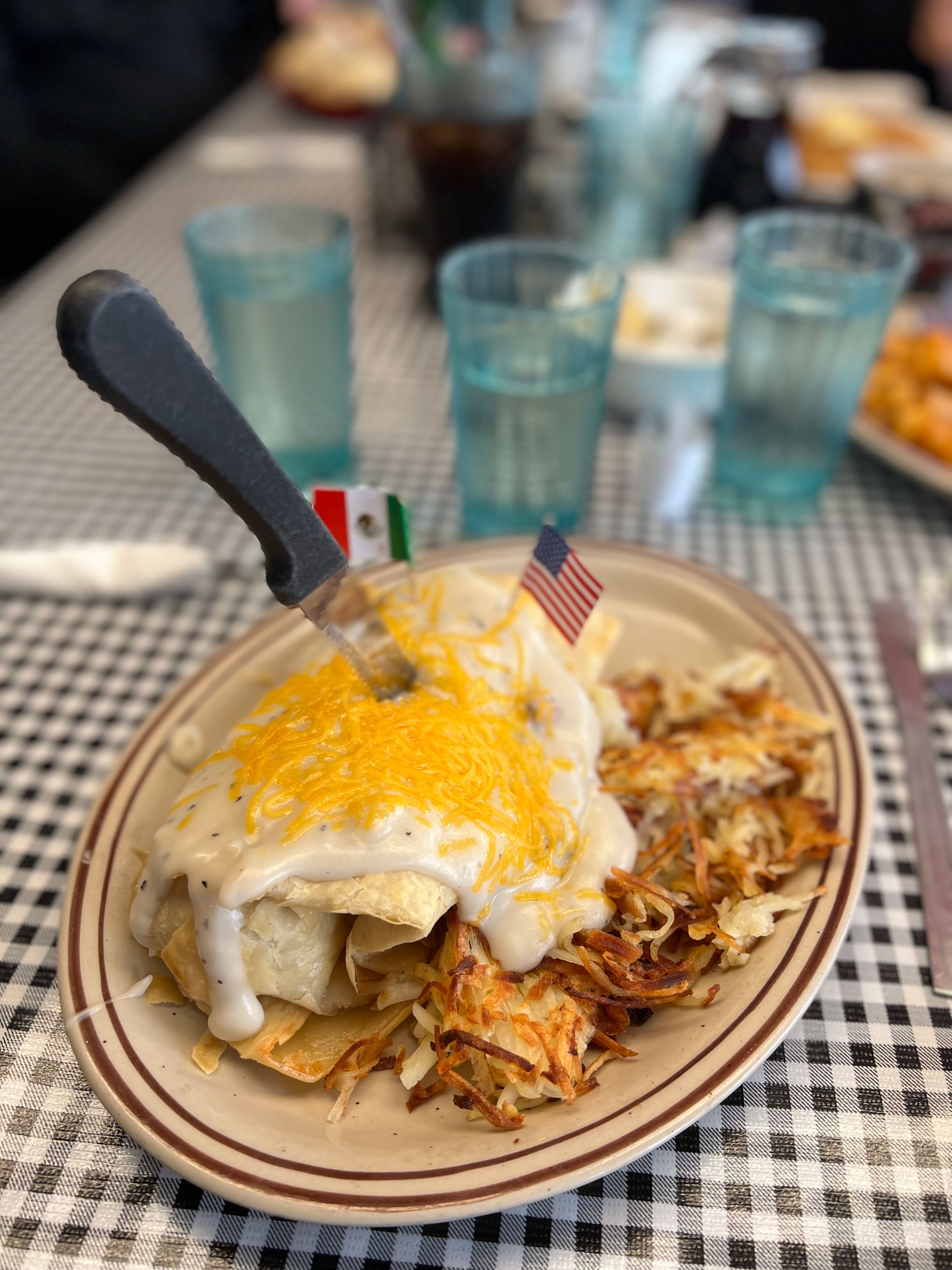 Plate of comfort food with melted cheese and checkered tablecloth.