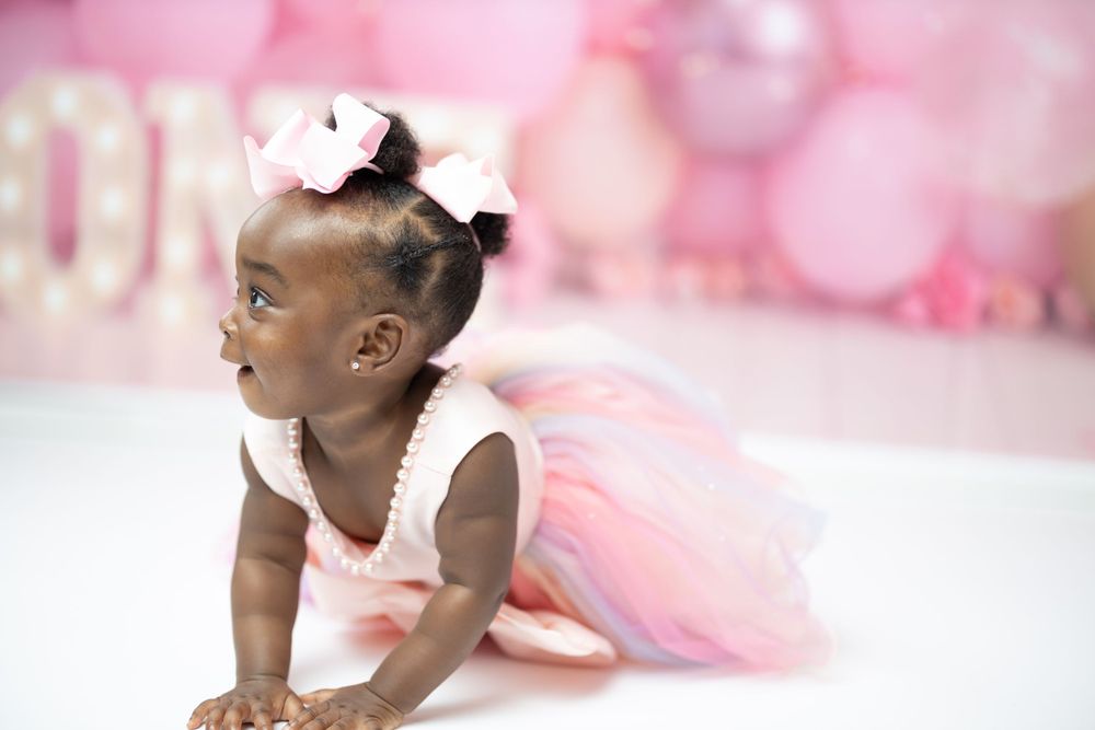Baby in pink tulle dress crawling during first birthday photoshoot.