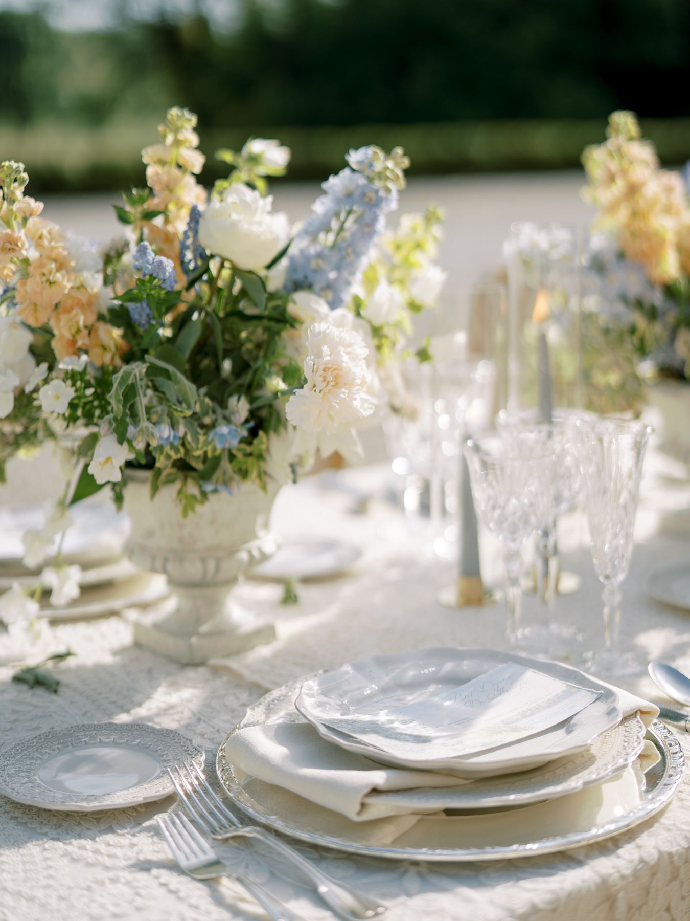An elegant table setting with delicate floral centerpieces in soft yellows and blues.