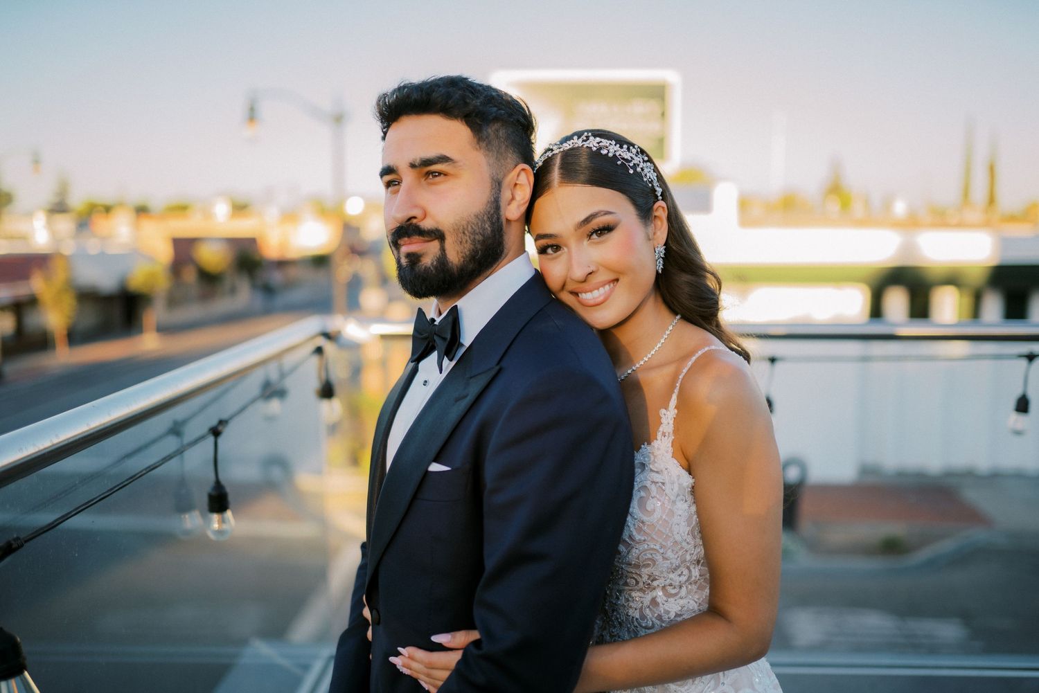 A romantic sunset wedding portrait captured on an outdoor terrace with city views.