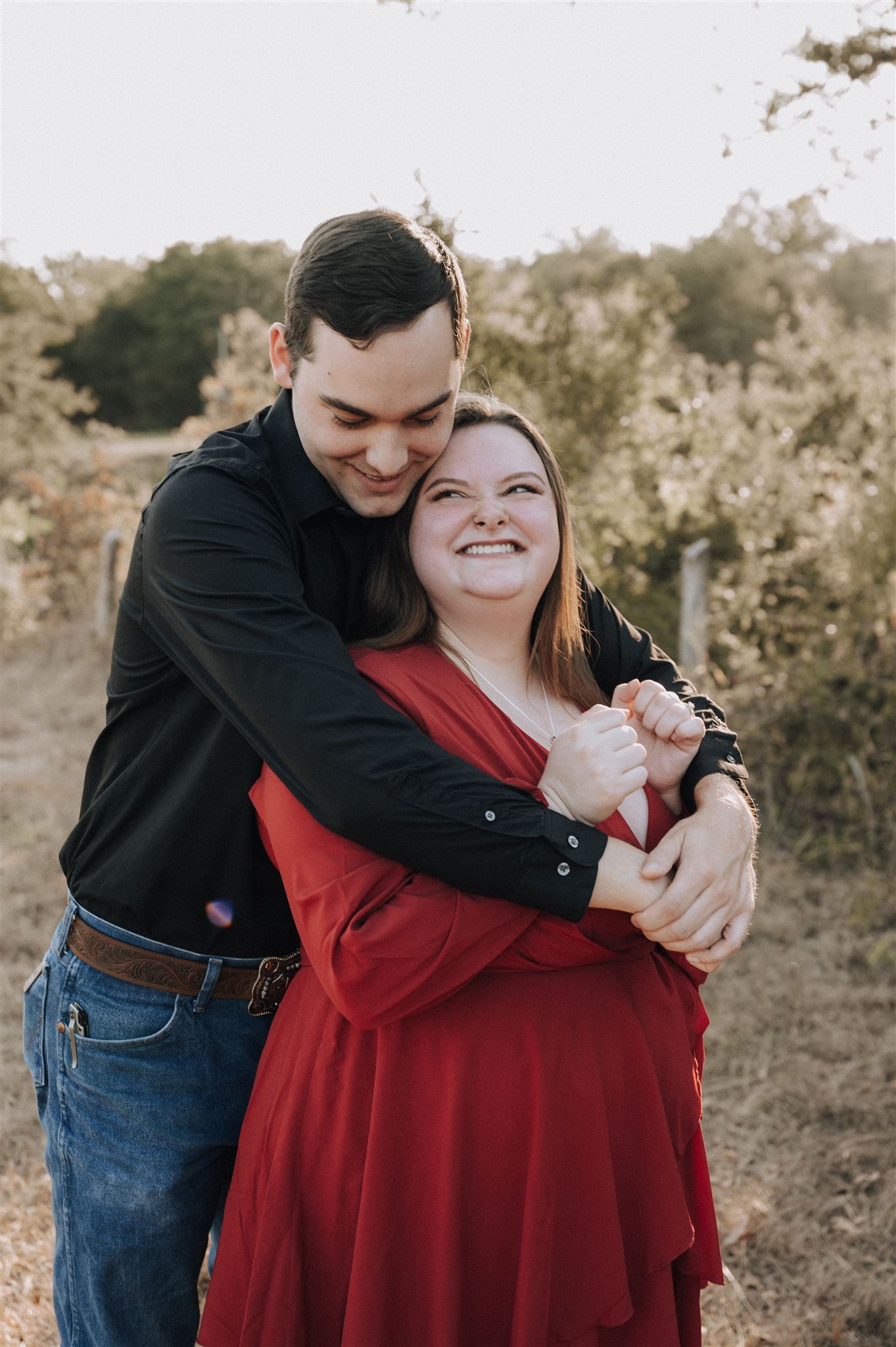 A joyful couple embraces while dancing in an outdoor setting during a photo session.