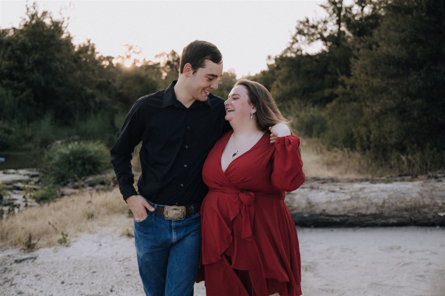 A romantic couple shares a moment together outdoors wearing coordinating black and red outfits.