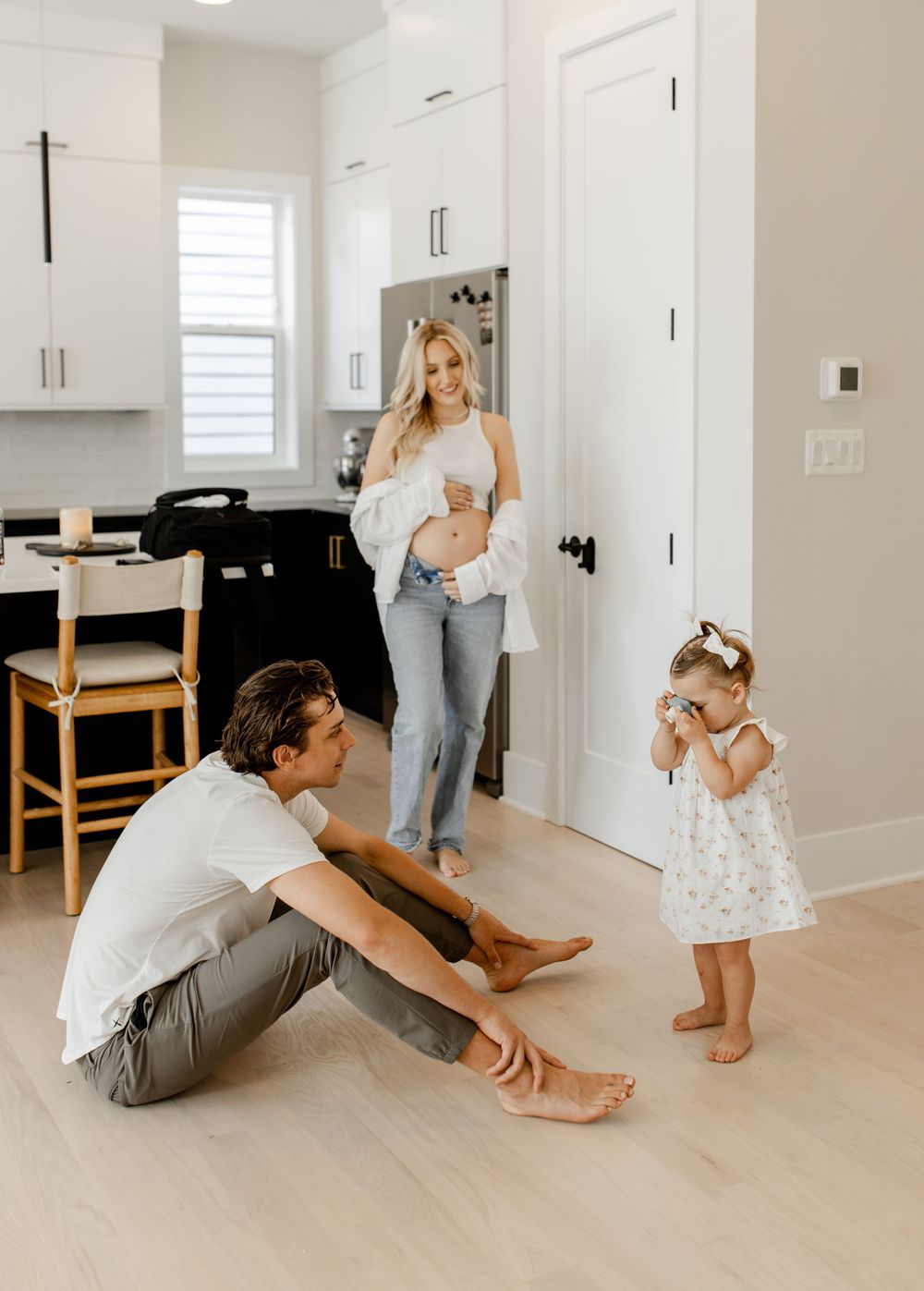 An intimate family moment in a bright modern kitchen with light hardwood floors.