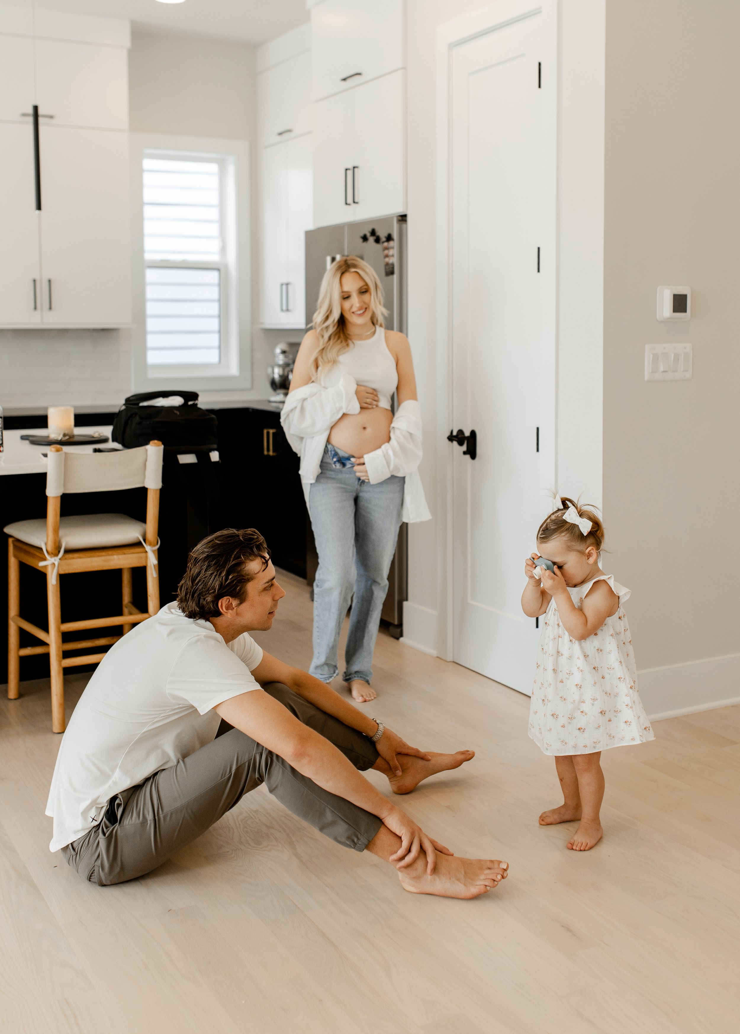 An intimate family moment in a bright modern kitchen with light hardwood floors.
