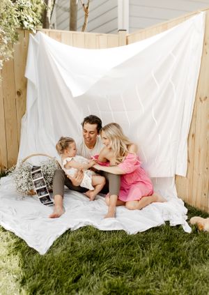 A family photo session outdoors with a white backdrop and baby's breath flowers.