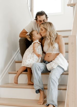 A tender family moment shared on wooden stairs in a bright, minimalist home.