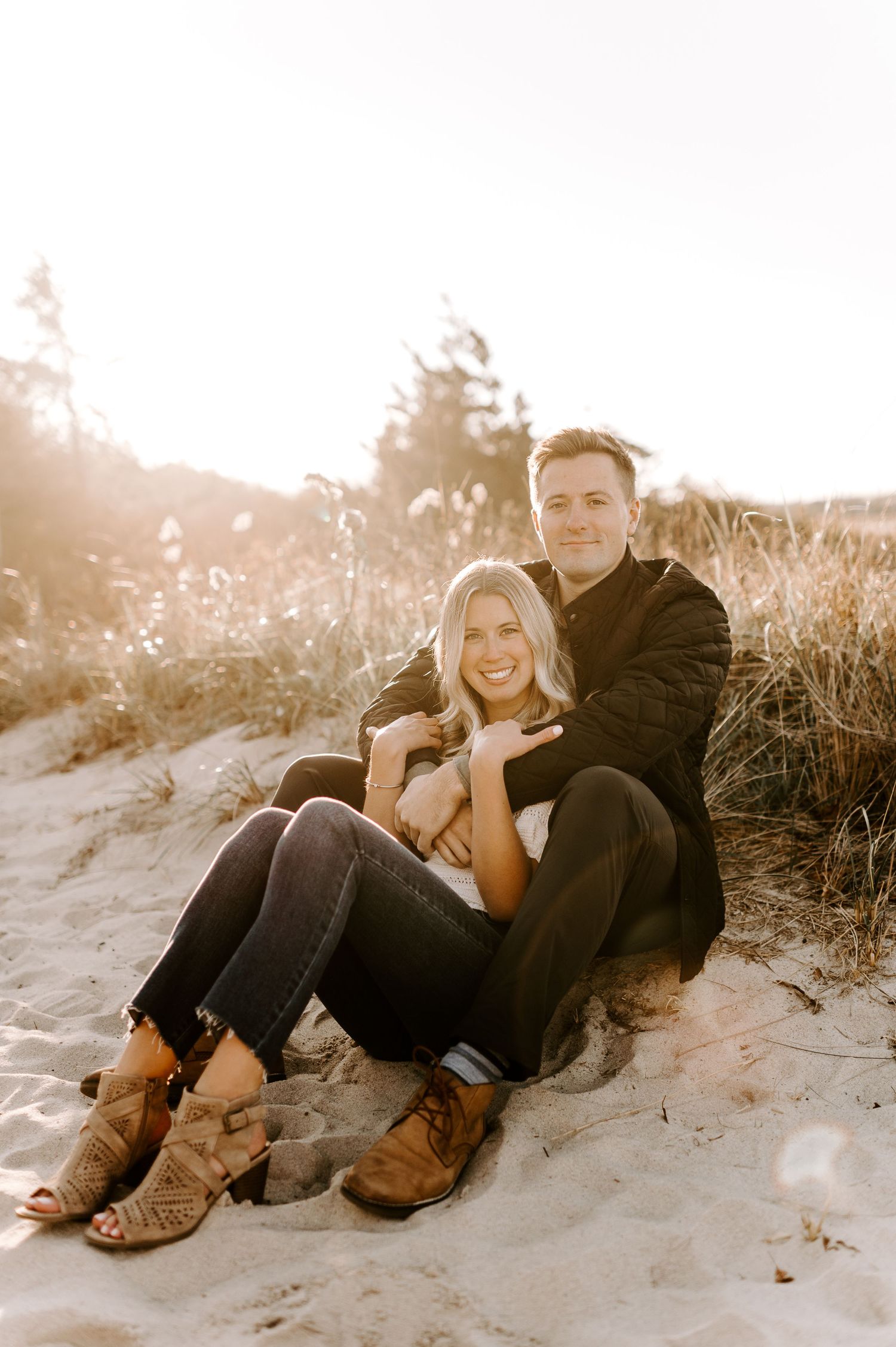 Romantic couple sharing intimate moment while resting on beach sand.