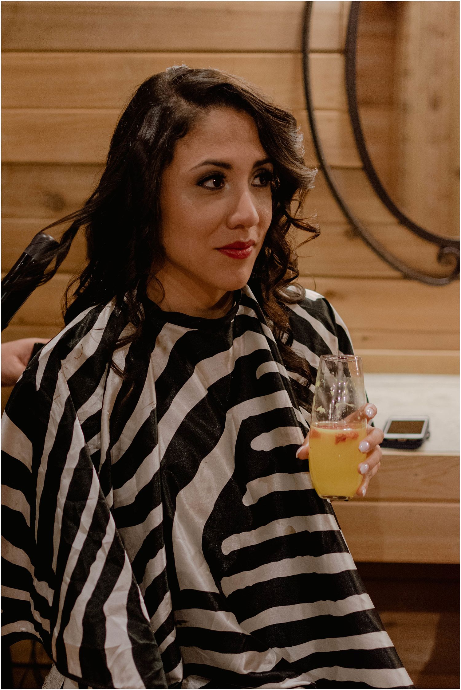 Interior scene with person wearing black and white zebra print robe holding beverage.