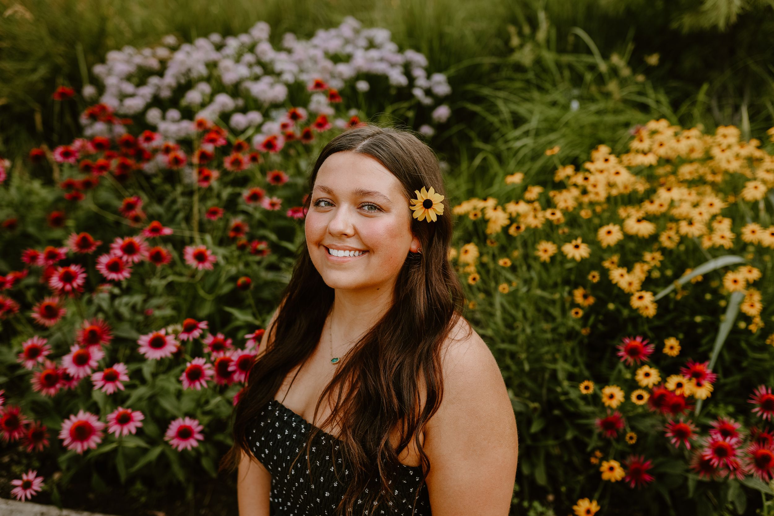Portrait in a colorful garden with pink and yellow flowers.