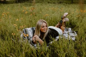 Person relaxing while reading in a wildflower meadow on a sunny day.