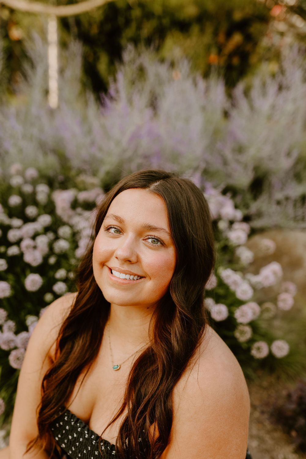 Portrait in a garden with blooming pink and purple flowers in the background.