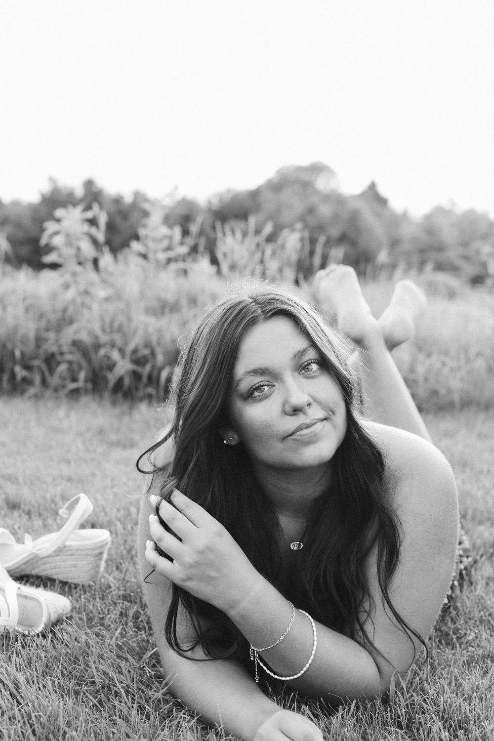 Black and white portrait of someone lying in grass with a natural pose.