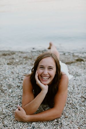 Person relaxing on a rocky beach while smiling at the camera.
