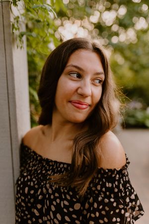 Portrait of person wearing black polka dot off-shoulder top with natural lighting.