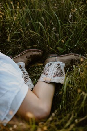 Close-up of embroidered western boots resting in tall grass.