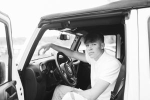 Person sitting in driver's seat of Jeep vehicle in black and white photo.
