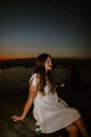 Person in white dress enjoying sunset view by the water.