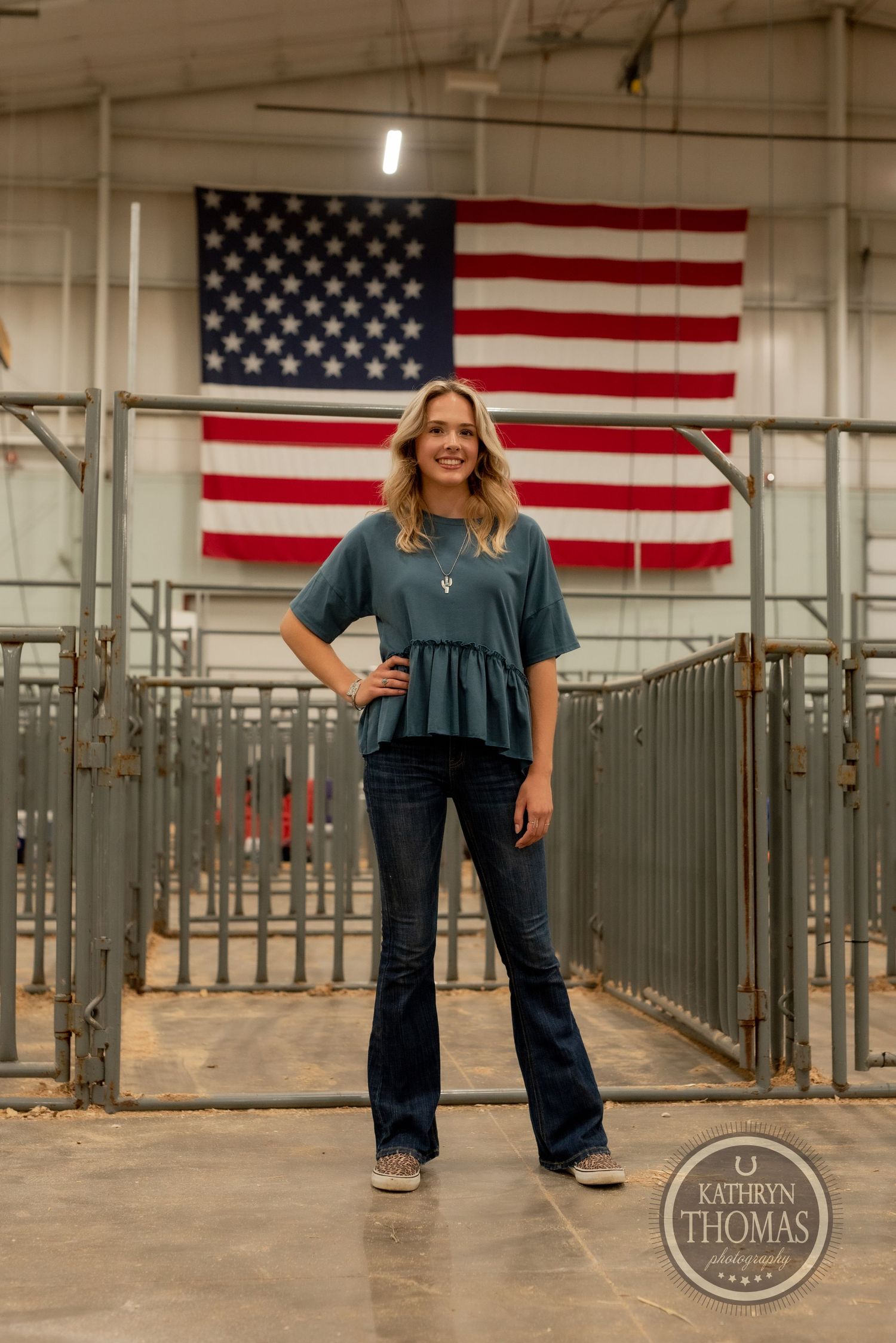 Casual fashion shoot with American flag backdrop features teal top and flared jeans.