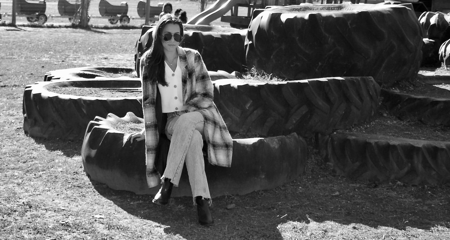 A vintage black and white photograph of someone sitting on the track of a military tank.