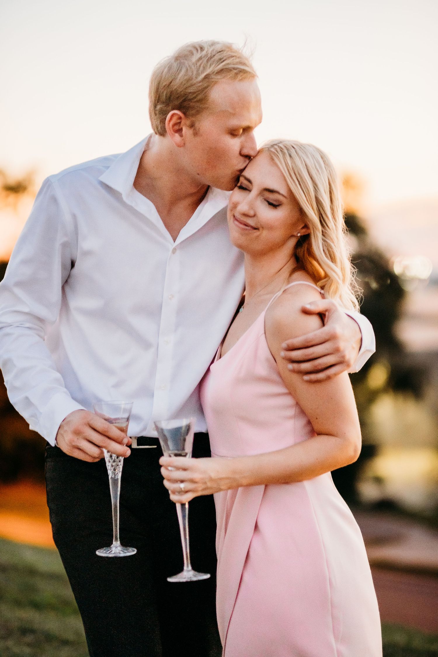 A couple stands with glasses at an engagement photography session at Union Station in Kansas City, Missouri.