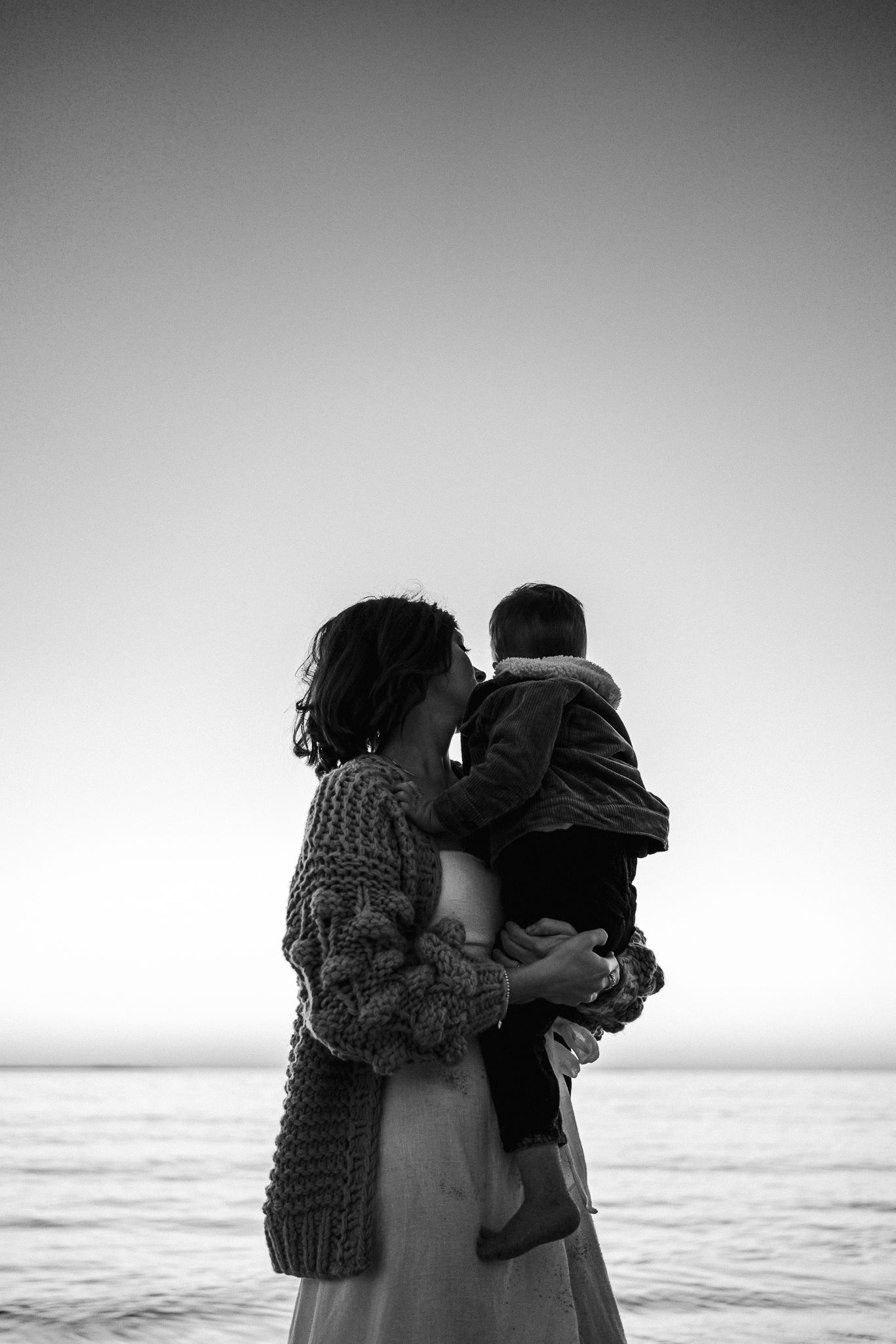 A mother and son hugging on the beach at sunset