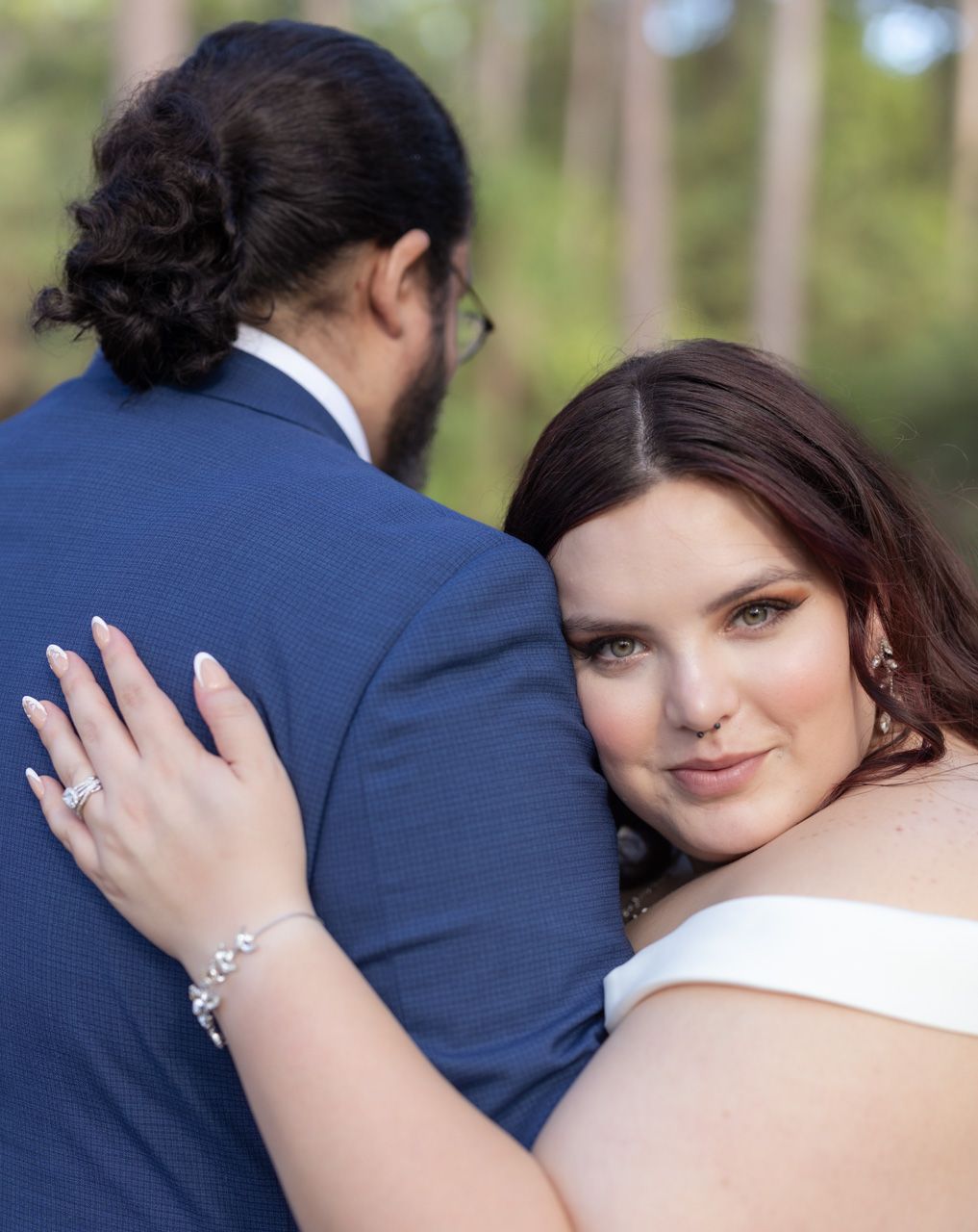 Close-up wedding portraits showing tender moments between newlyweds in forest setting.