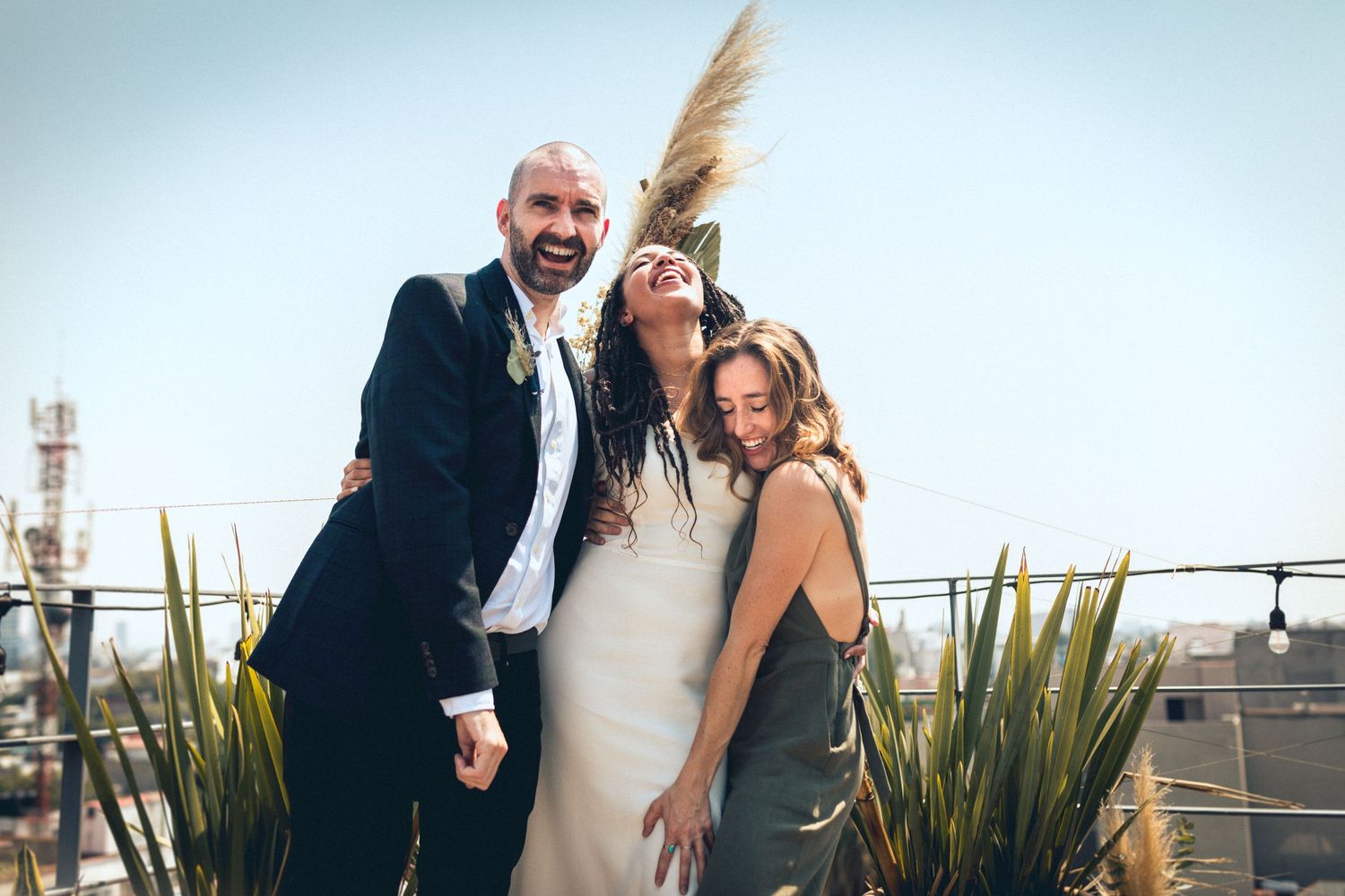 Wedding party members laugh and embrace during an outdoor photo session with desert plants in background.