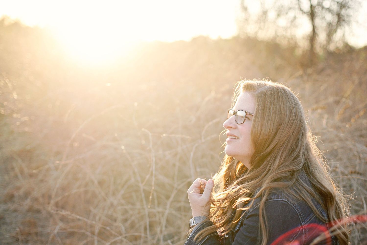 A woman with blonde hair enjoying golden hour sunlight in an outdoor setting.