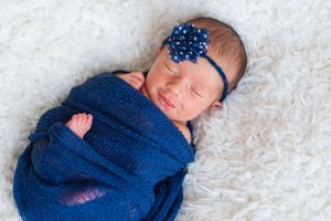 Newborn baby girl swaddle wrapped custom headband soft focus sweet baby little bundle of smile captured sleepy baby Alabama Fairhope