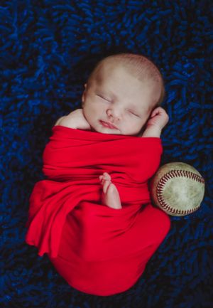 newborn boy pose natural light photography studio session wrap baseball custom creative set memory captured Alabama Baldwin county sleeping