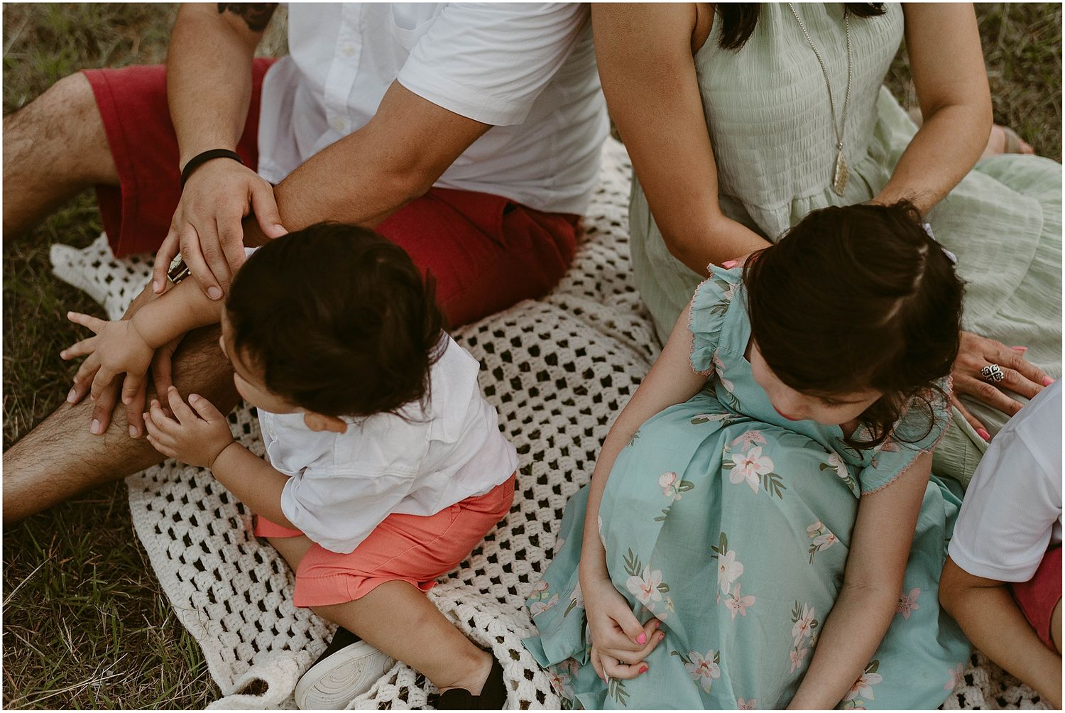 Intimate family moments shared while relaxing on a patterned blanket in nature.