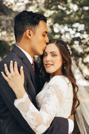 Intimate Tucson wedding portrait of a groom kissing his bride’s forehead in soft natural light.