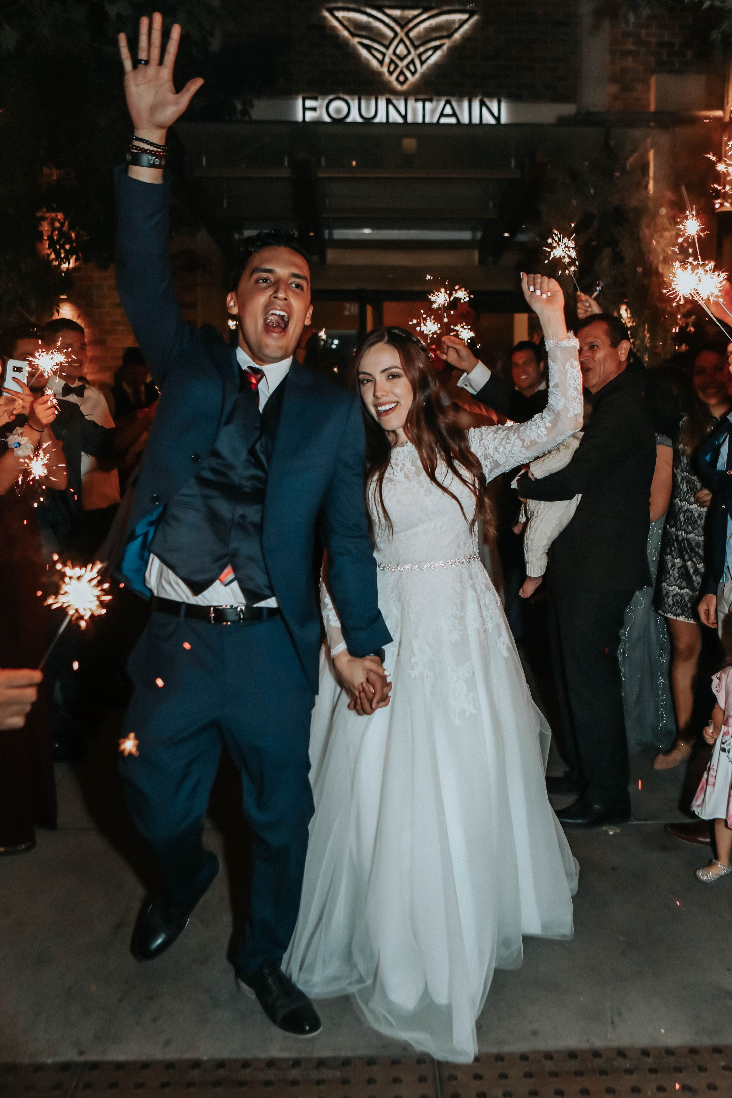 Tucson wedding reception exit with bride and groom celebrating as guests cheer and hold sparklers.
