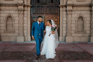 Elegant Tucson wedding photo of a bride and groom posing in front of historic architectural doors.