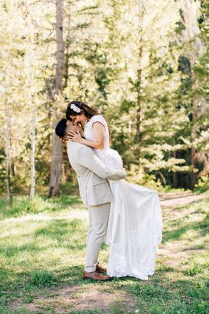 Tucson couples portrait of a man lifting his partner in a sunlit forest, capturing joyful, romantic moments.