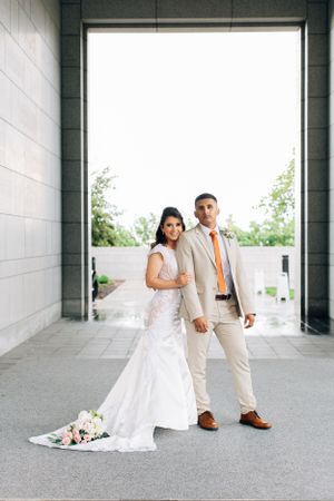 Tucson wedding portrait of a bride and groom holding hands under an archway, with the bridal bouquet resting nearby.