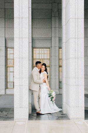 Romantic Tucson wedding photo of a newlywed couple standing together in a stone-column walkway.