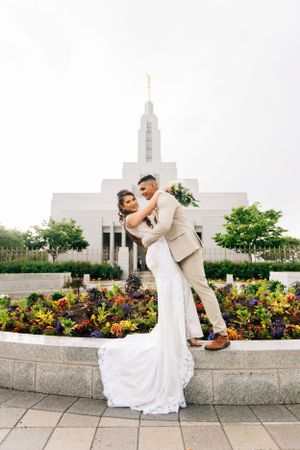 Joyful Tucson wedding portrait of a bride and groom celebrating outside the temple with colorful flowers and greenery.