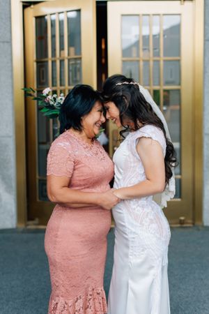 Tucson wedding day moment of a bride and her mother sharing an emotional embrace in front of gold double doors.